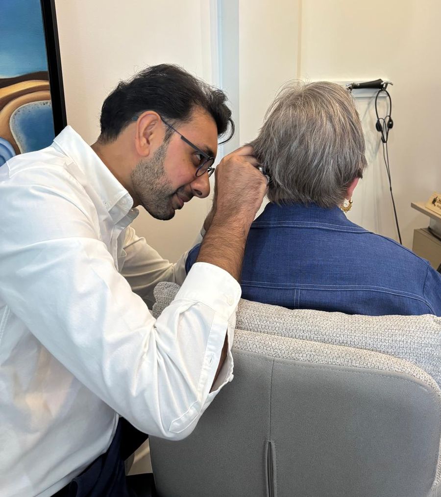 Shoël, audioprothésiste, place une aide auditive sur l'oreille d'une patiente au centre AuditionVision de Bagneux